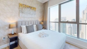 A modern hotel room with a large bed, a city view, and a textured wall.