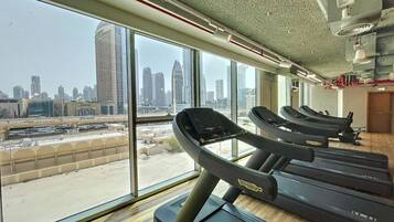 A gym with treadmills, large windows, and a view of a cityscape.