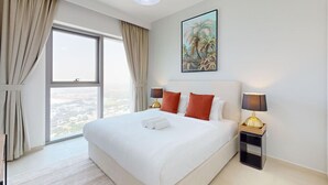 Habitación de hotel con una cama grande, dos lámparas de noche, una mesita de noche, un cuadro en la pared y vistas por la ventana.