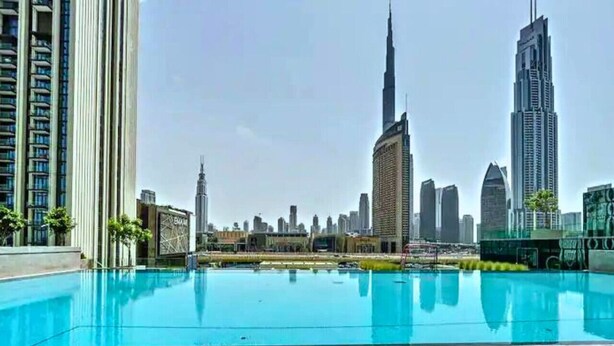Una piscina en la azotea con el horizonte de la ciudad al fondo.