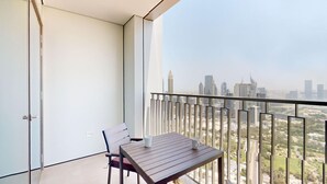 Un balcón con mesa y sillas, con vistas a un paisaje urbano de edificios modernos.
