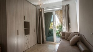 A modern living room with a sofa, a built-in wardrobe, and a sliding glass door leading to a balcony.