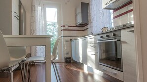 A modern kitchen with stainless steel appliances, a wooden floor, and a view of the outdoors.