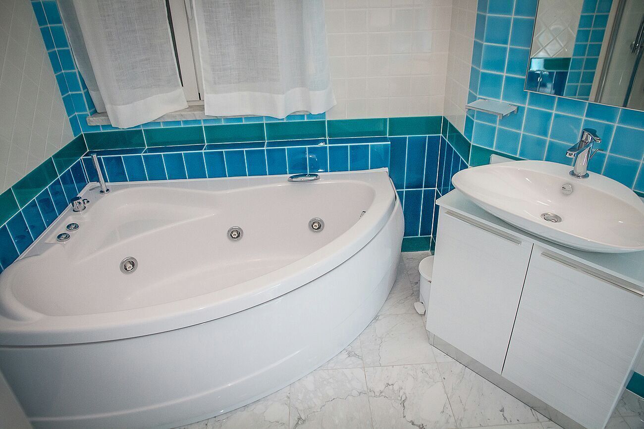 Un bagno con una vasca, un lavandino e uno specchio.