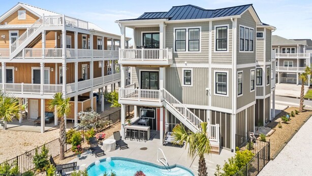 A multi-story hotel with balconies, a swimming pool, and outdoor seating. - Oasis Vacations, Sweet Tater, Pool, Elevator, Putting Green, Marsh Views (Ocean Isle Beach)