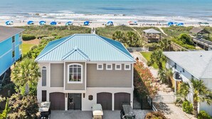 A two-story house with a blue roof, a garage, and a driveway. - Oasis Vacations, Sweet Tater, Pool, Elevator, Putting Green, Marsh Views (Ocean Isle Beach)