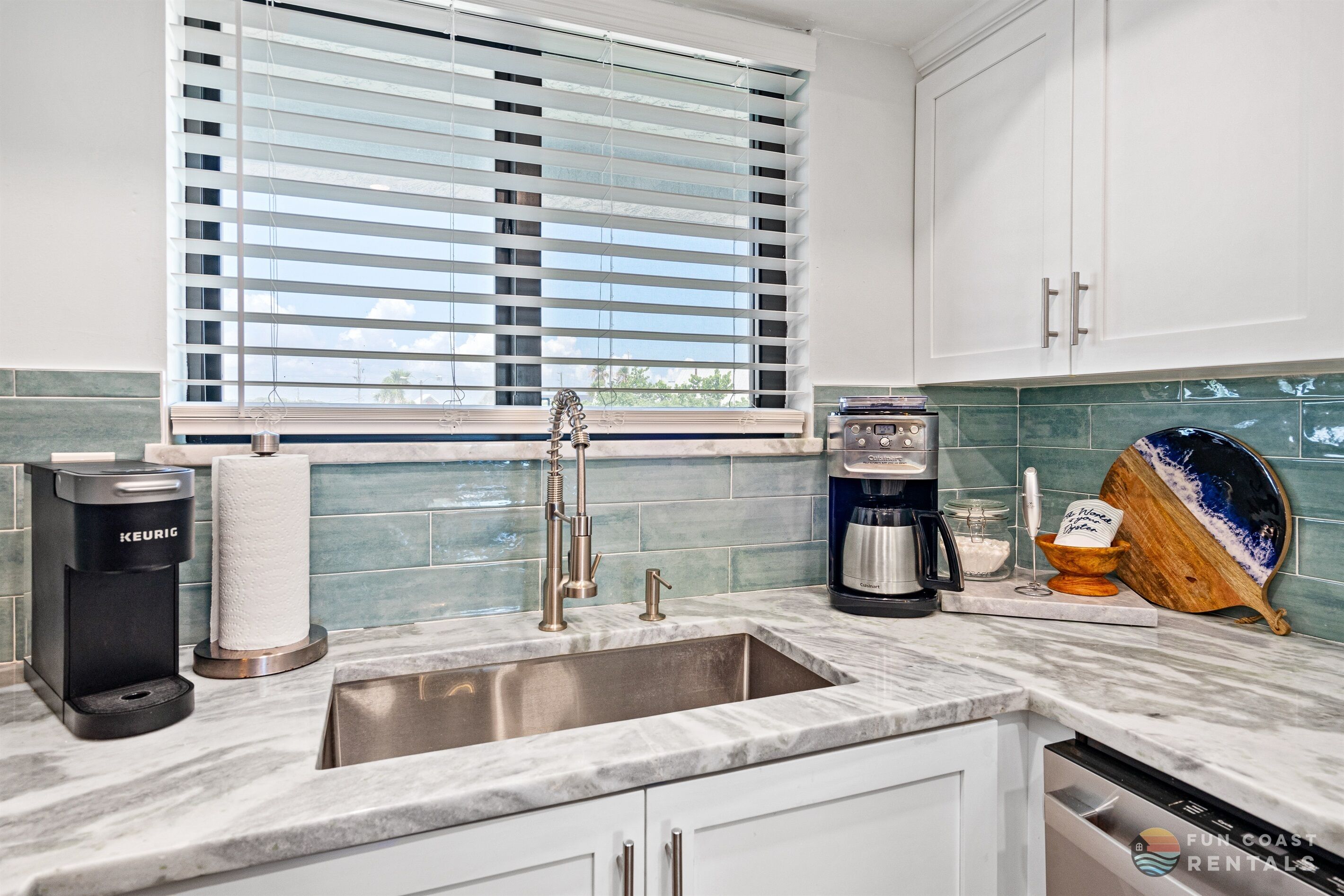 A modern kitchen with a built-in sink, a coffee maker, and a wooden cutting board.