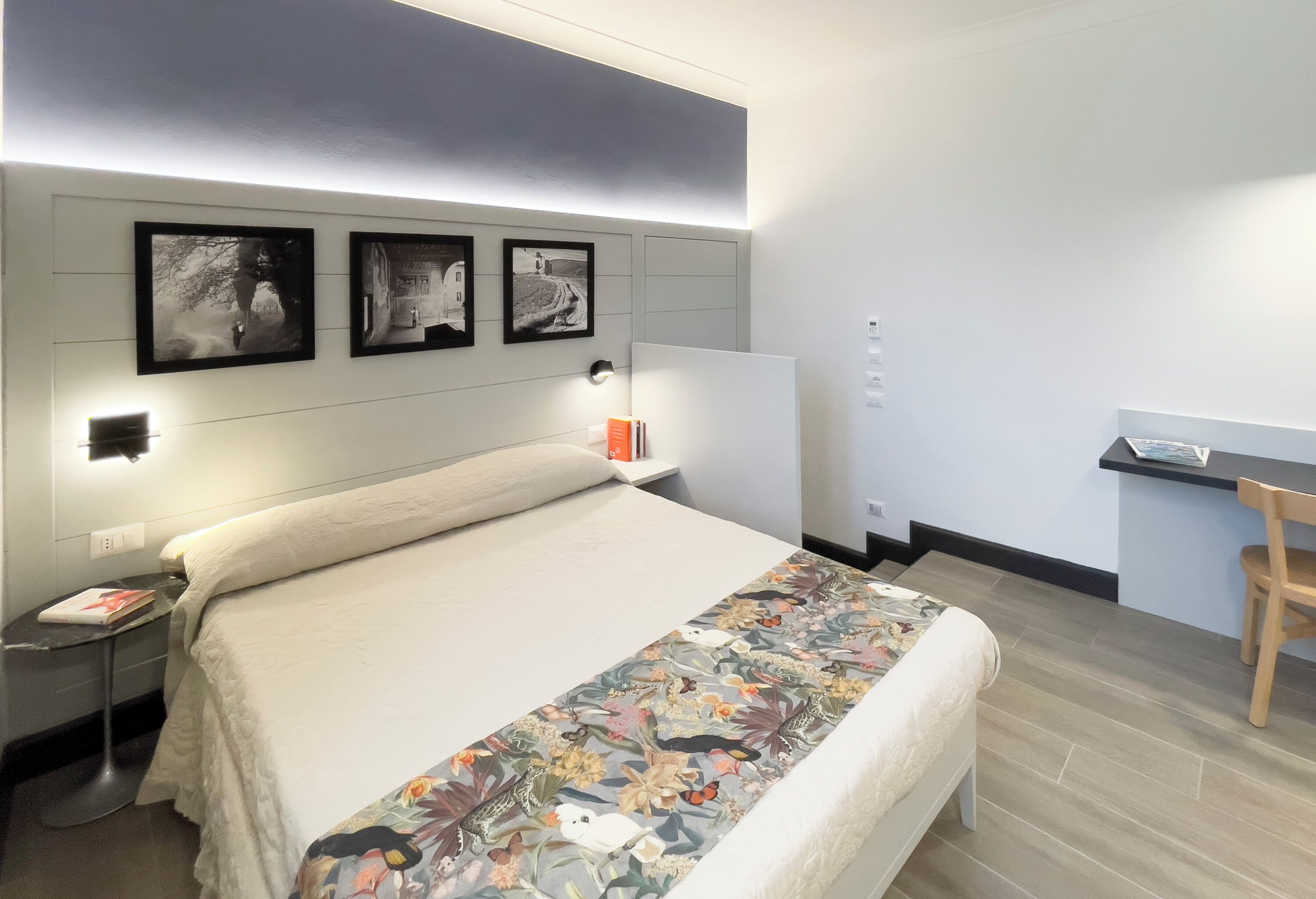 Una camera da letto moderna con un letto grande, una scrivania e tre quadri appesi al muro.