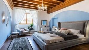 Un dormitorio con una cama grande, una silla, una mesita de noche y una araña.