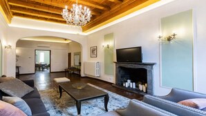 Una sala de estar con chimenea, televisor y candelabro.