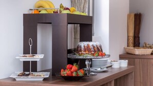 Un buffet proposant une variété de fruits, un gâteau en forme de couronne et des pâtisseries, le tout disposé sur une table en bois.