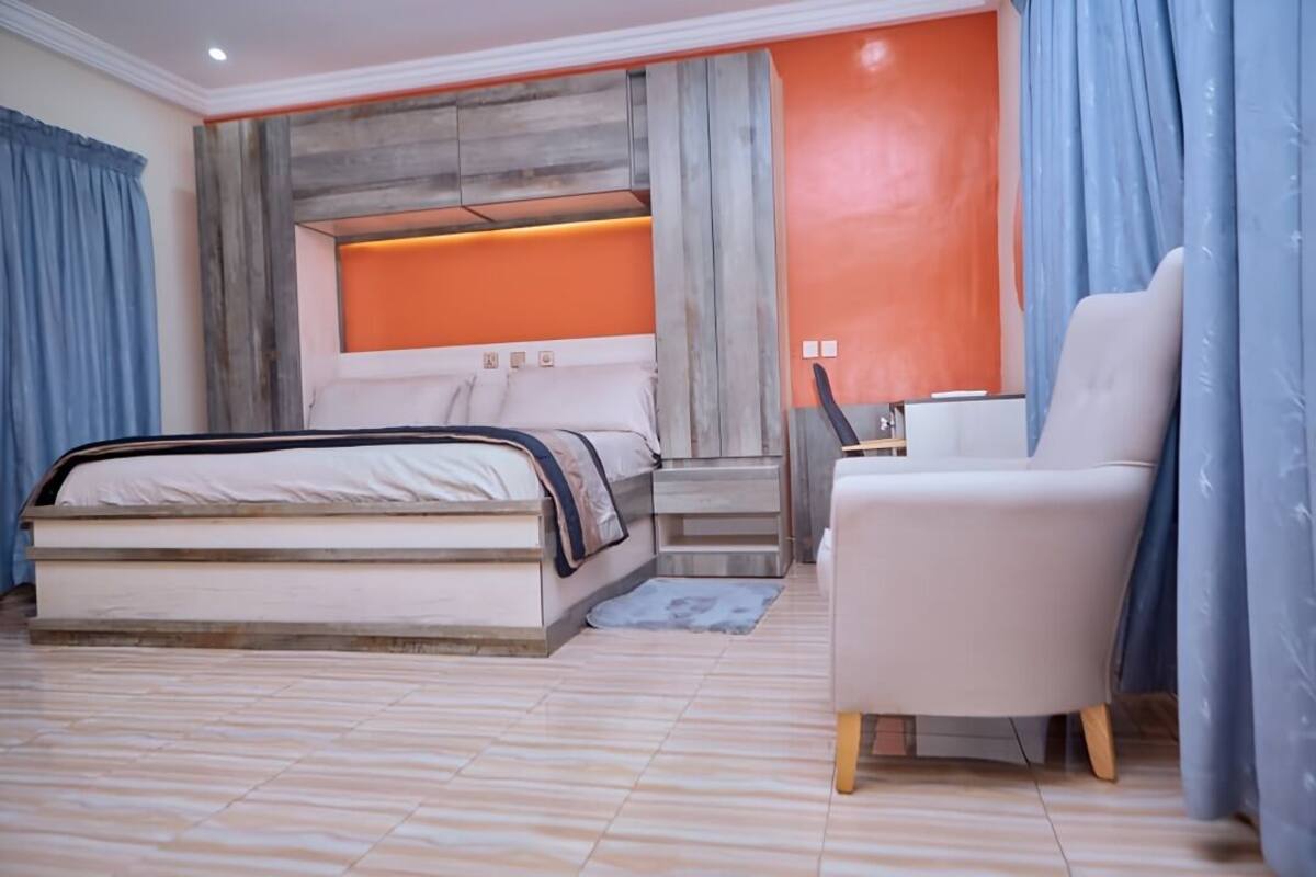 A modern bedroom with a bed, a chair, and a desk.