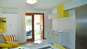 A modern kitchen with a refrigerator, a dining area with a table and chairs, and a living room with a sofa and cushions. - Seaside Apartment in Santa Cruz Tenerife (Lignano Sabbiadoro)