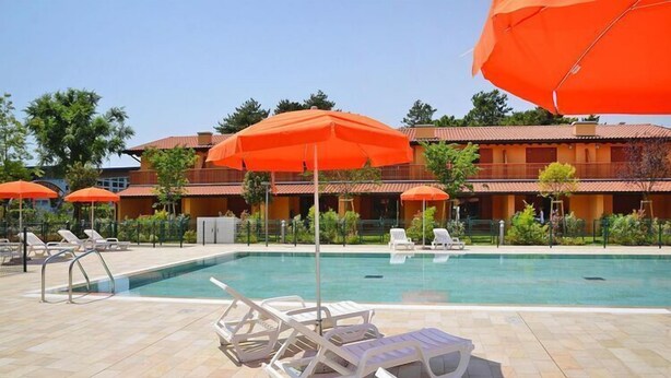 A swimming pool with lounge chairs and orange umbrellas. - Seaside Apartment in Santa Cruz Tenerife (Lignano Sabbiadoro)