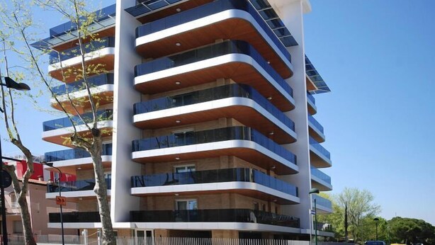 A multi-story building with balconies, a clear sky, and trees. - Apartment near the beach in Lignano (Lignano)
