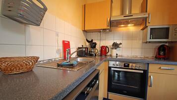 A kitchen with a sink, stove, microwave, and various appliances.