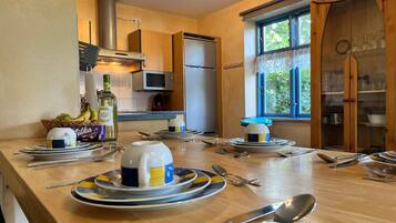 A well-lit kitchen with a dining table set for four, equipped with modern appliances and a large window providing natural light.