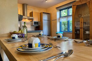 A well-lit kitchen with a dining table set for four, equipped with modern appliances and a large window providing natural light.
