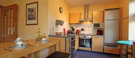 A compact kitchen with a dining area, a microwave, a stove, and a refrigerator.