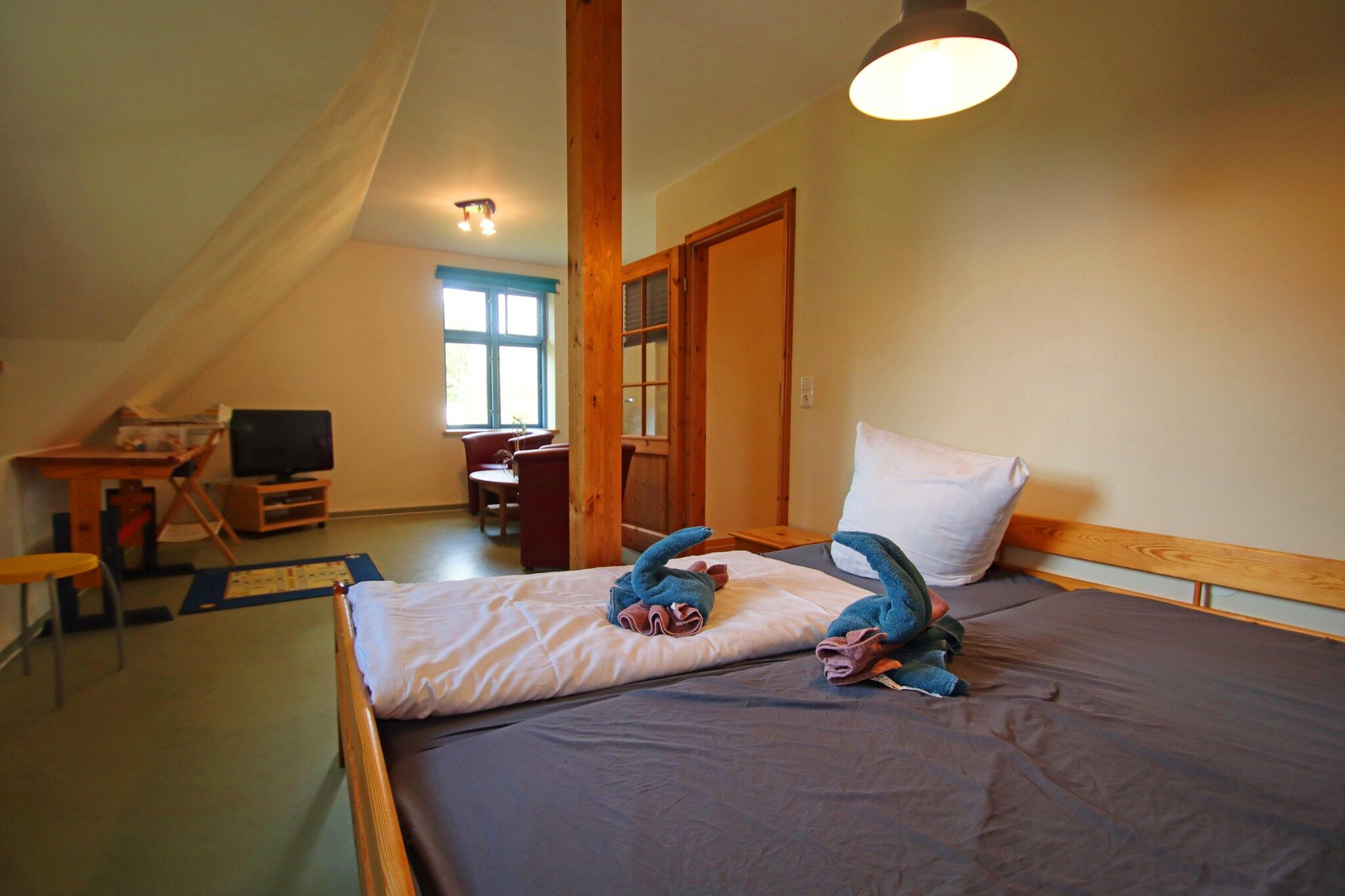 Une chambre à coucher avec un lit, un bureau, une chaise, une télévision et une fenêtre.