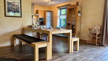A compact kitchen with wooden furniture, a dining table, and a bench.
