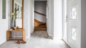 Un pasillo con una consola de madera, un espejo y un par de zapatos en el suelo.