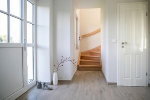 Staircase leads to a hallway with a door, window, and decorative vase.
