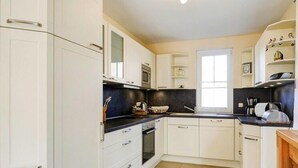 A modern kitchen with white cabinets, a black countertop, and a window. - Ferienhaus Nachtigall, Glowe (Glowe)