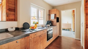 A modern kitchen with wooden cabinets, a built-in oven, and a large window.
