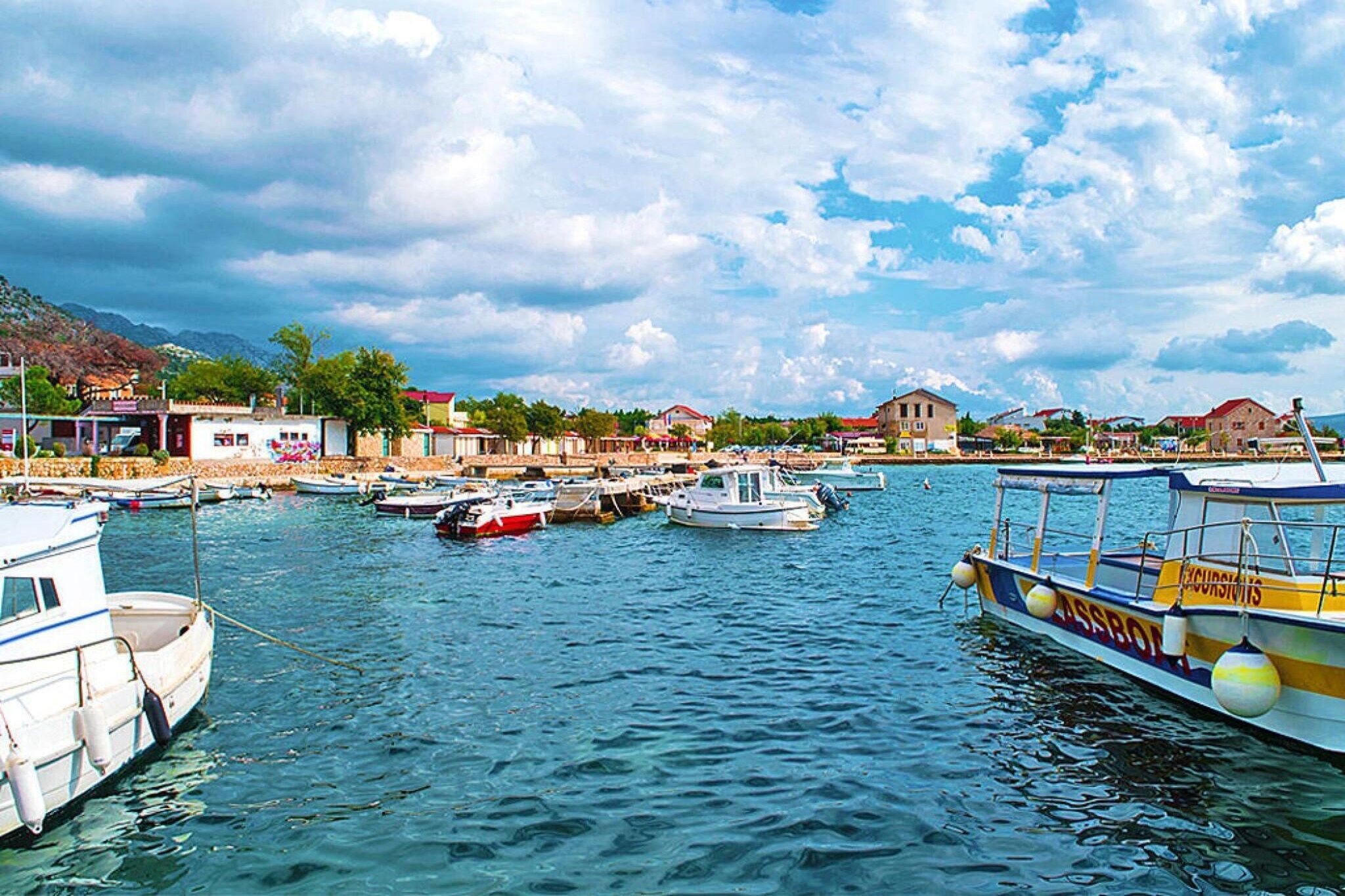 A marina with several boats docked, a clear sky, and buildings in the background.