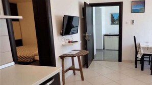 Une chambre d’hôtel de taille réduite, comprenant un lit, un petit bureau, une télévision et un coin repas.