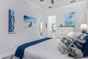 A bedroom with a bed, a dresser, a mirror, and wall art.