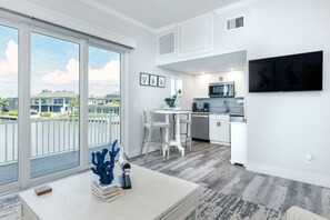 A modern kitchen with white cabinets, a microwave, and a dining area with a white table and chairs. - Manatee Suite 1 Funky Fish House at Cape Harbour (Cape Coral)