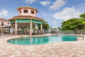 A swimming pool with a covered pavilion, lounge chairs, and a lifebuoy.