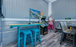 A gaming area with a pool table, blue stools, and a person in Santa costume.