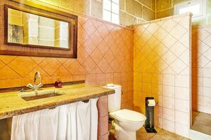 Une salle de bain équipée d’un lavabo, d’un miroir, de toilettes et d’un espace douche.