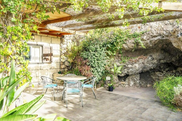 A patio with a stone wall, a table with chairs, and potted plants.