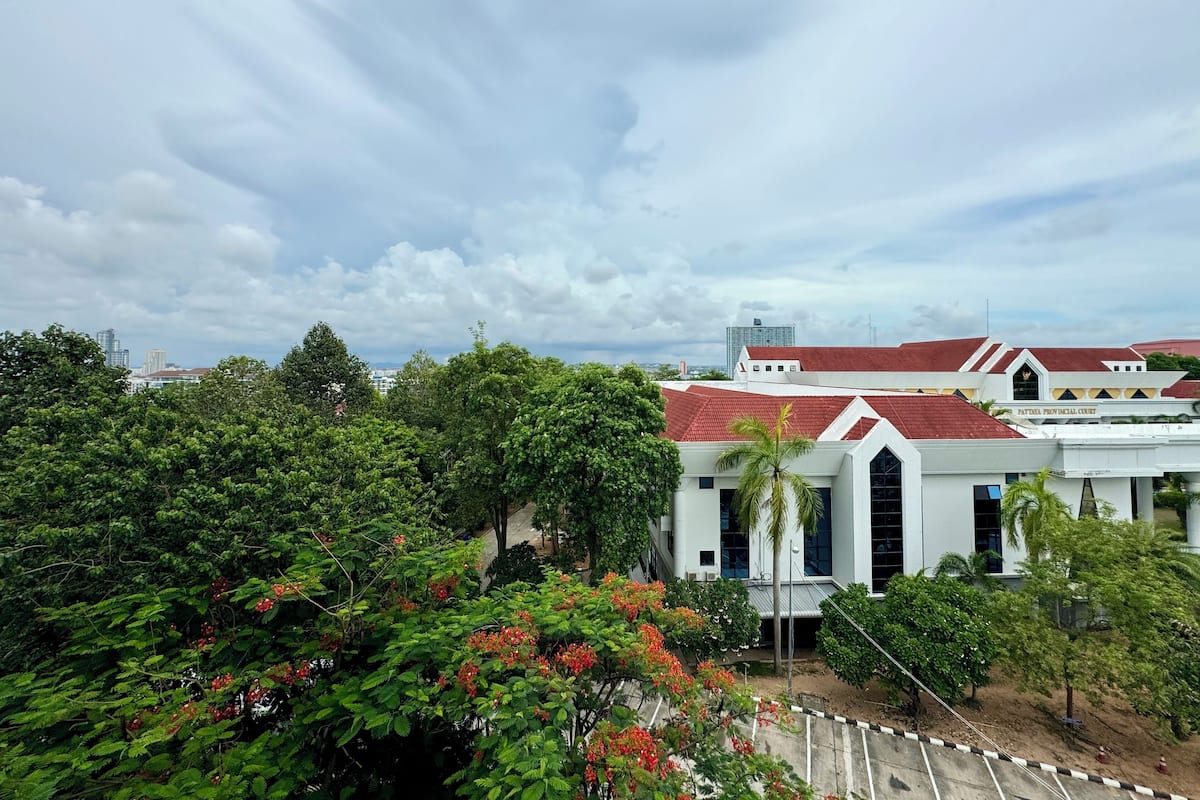 A courthouse with a red roof, surrounded by lush greenery and trees.