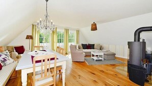 A cozy living room with a dining area, a sofa set, a fireplace, and a chandelier. - Ferienwohnung in Wyk auf Foehr (Wyk auf Föhr)