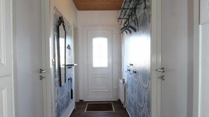 Un couloir doté d’un plancher en bois, de portes blanches et d’un luminaire au plafond.