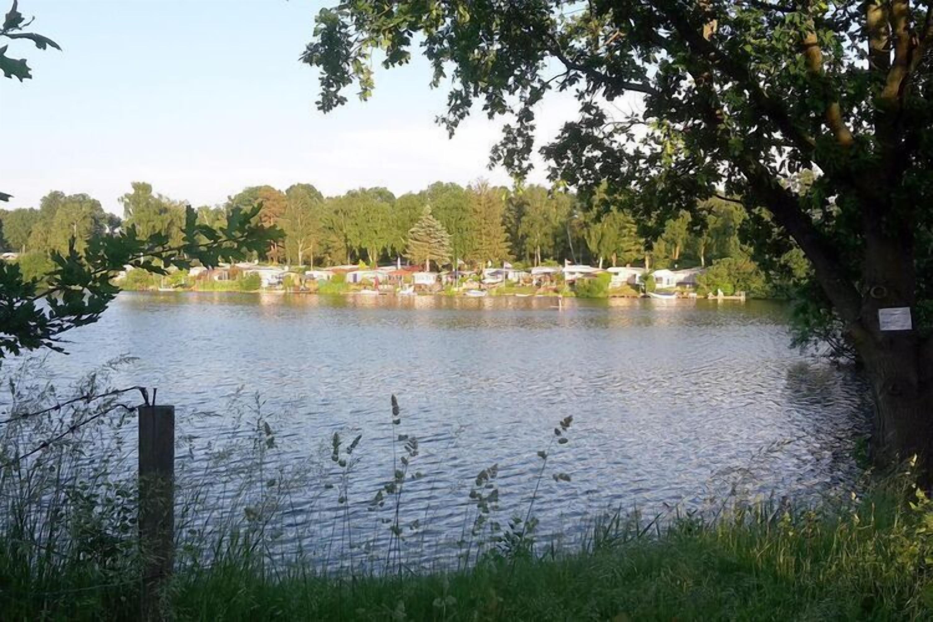 Un lago con una hilera de cabañas al fondo.