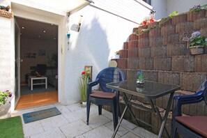 Un patio con una mesa y sillas de vidrio, un muro de ladrillo y un felpudo.