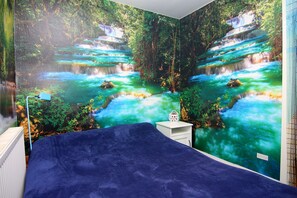 Un dormitorio con un gran mural de una cascada y abundante vegetación.