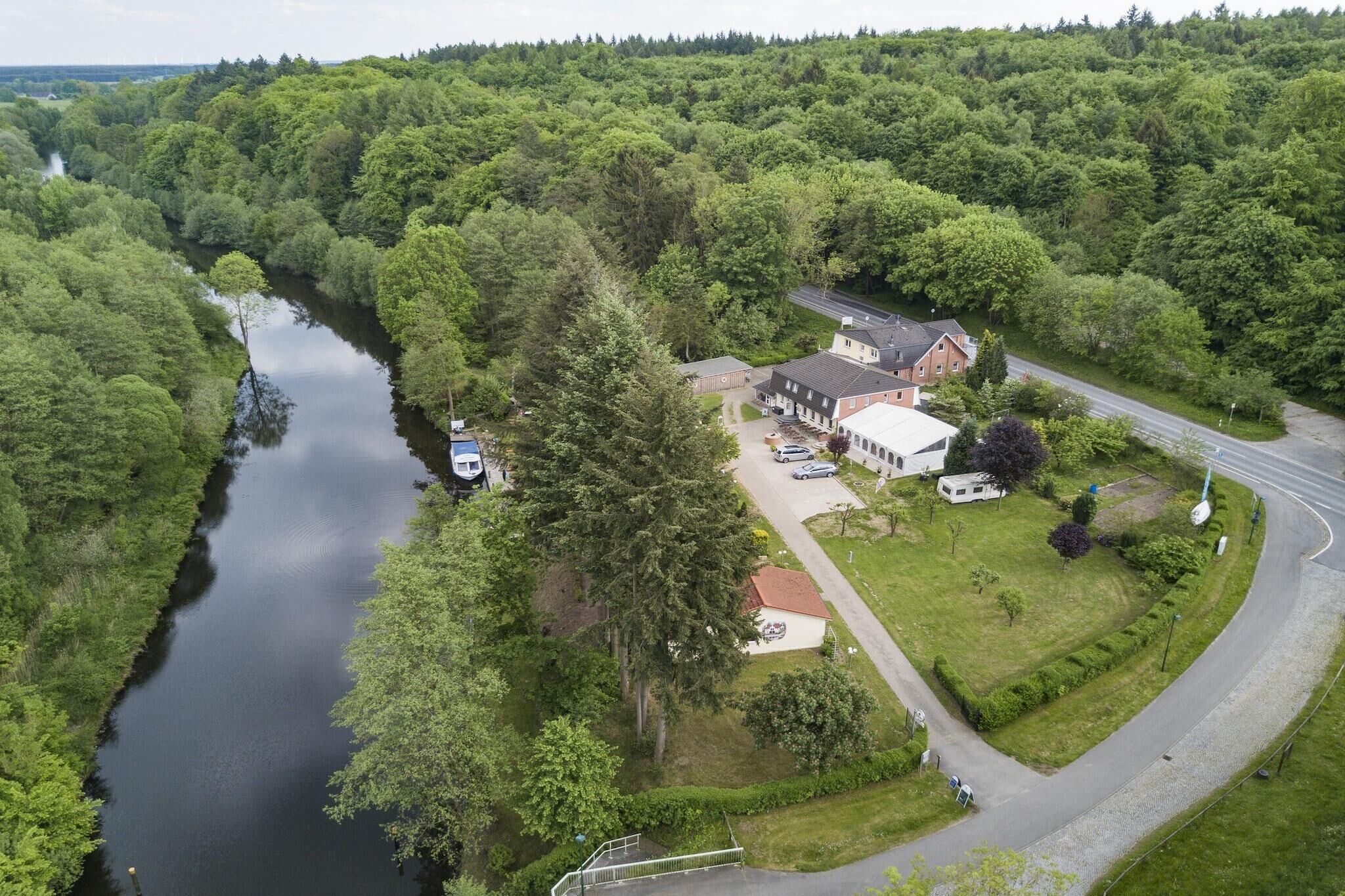 A riverside property with a main building, a parking area, and a road curving around the property.