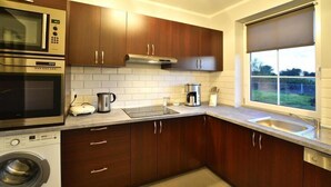 Cucina moderna con mobili in legno, forno integrato, microonde e lavatrice.