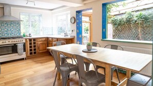 A kitchen with wooden cabinets, a stove, and a dining table with chairs. - Charming Frome Retreat With 4 Bedrooms (Frome)