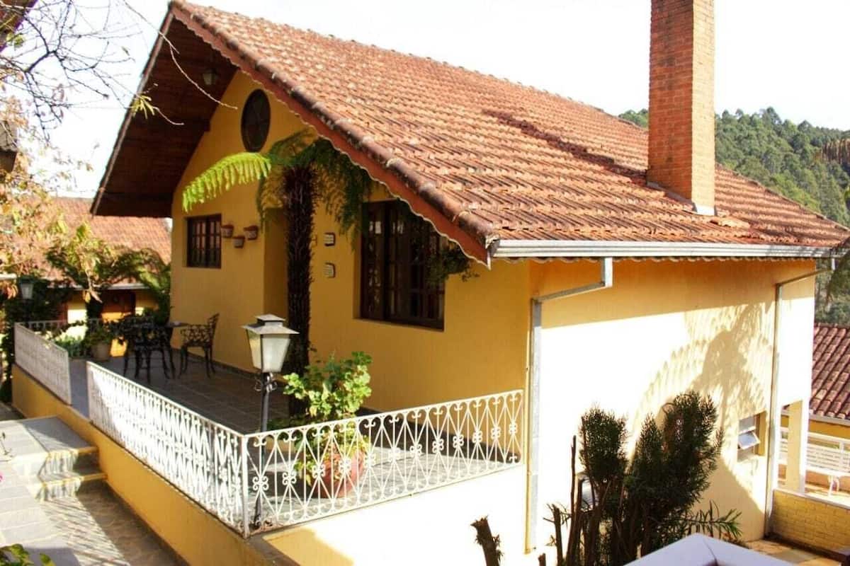 Ein gelbes Gebäude mit einem Ziegeldach, einem Balkon mit weißer Brüstung und Topfpflanzen.