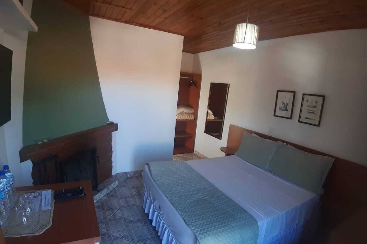 Ein Schlafzimmer mit einem Bett, einem Schreibtisch mit Stuhl, einem Spiegel und einem kleinen Tisch mit Gegenständen.