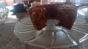 A cake on a clear glass cake stand with a central hole.