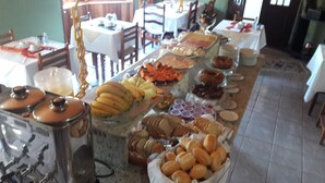 A buffet with various food items including fruits, pastries, and beverages. - POUSADA BELA VISTA (Camanducaia)